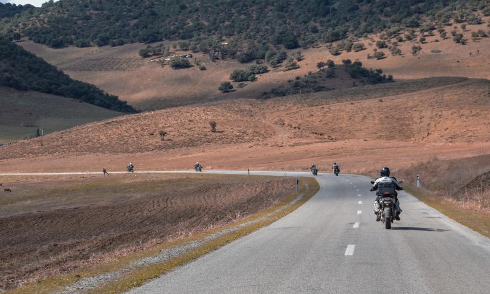 plusieurs motards sur route courbe