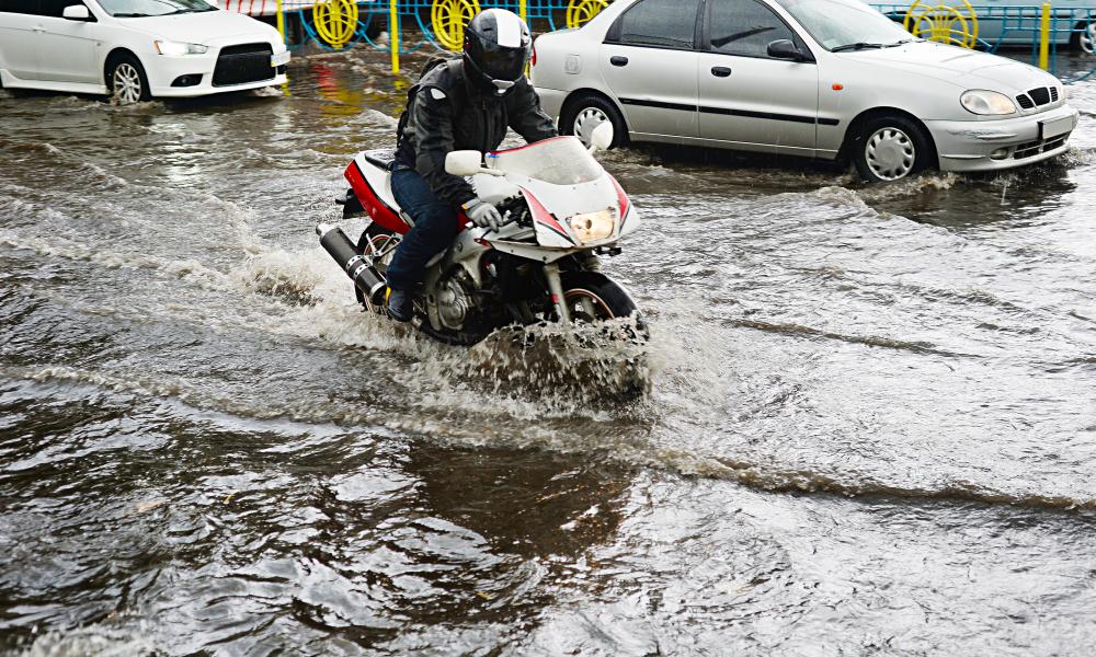 motard roule sur route inondée